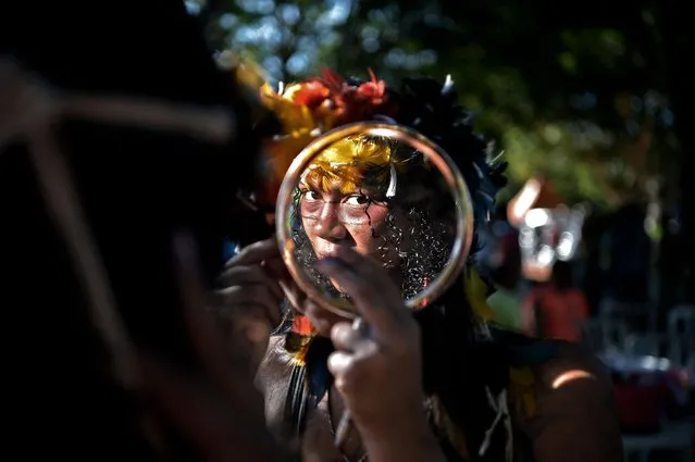 A woman of the Truka tribe looks at herself in the mirror on the fourth day of the Terra Livre Indigenous Camp in Brasilia, on April 7, 2022. The 10-day annual protest is held by indigenous people from tribes that arrive from all over Brazil, and calls for greater protection of their land and rights. (Photo by Carl de Souza/AFP Photo)