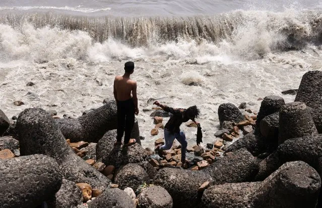 Boys watch waves hit the shore in Mumbai, India on June 12, 2023. (Photo by Francis Mascarenhas/Reuters)