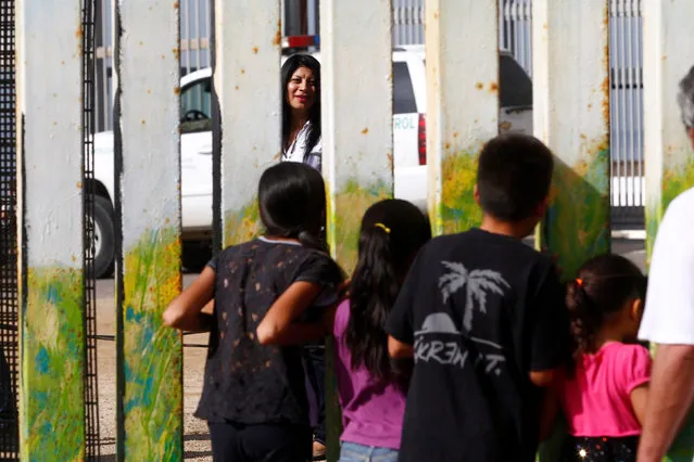 A woman in Friendship Park in San Diego, California, U.S. speaks with children across a fence separating Mexico and the United States, November 12, 2016. Picture taken from Tijuana, Mexico. (Photo by Jorge Duenes/Reuters)