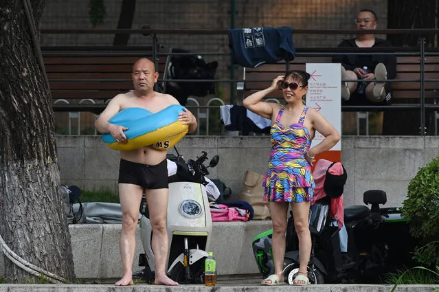 A man and woman relax after swimming in a canal during a heatwave in Beijing on June 23, 2023. (Photo by Greg Baker/AFP Photo)