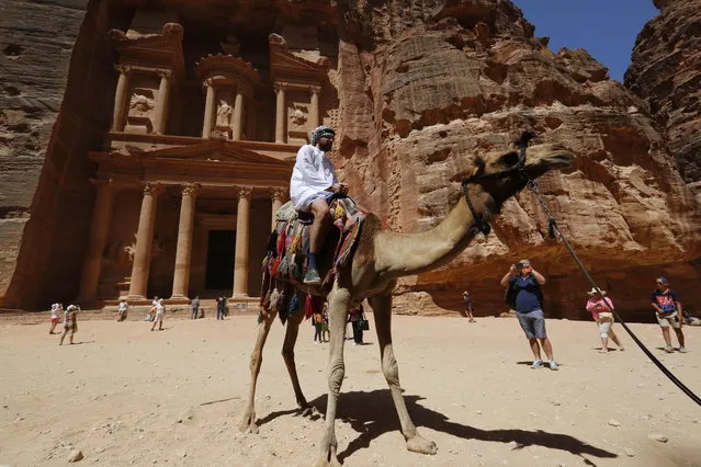 Tourists visit a famous monument, the Treasury, at the rock-carved rose-red city of Petra, Jordan, 27 July 2018 (issued on 29 July 2018). Jordan's ancient city of Petra, one of the most famous archaeological sites in the world, is believed to have been settled as early as 9,000 BC, and it possibly began to prosper as the capital of the Nabataean Empire from the 1st century BC. Petra is designated a World Heritage Site since 1985. (Photo by Yahya Arhab/EPA/EFE)