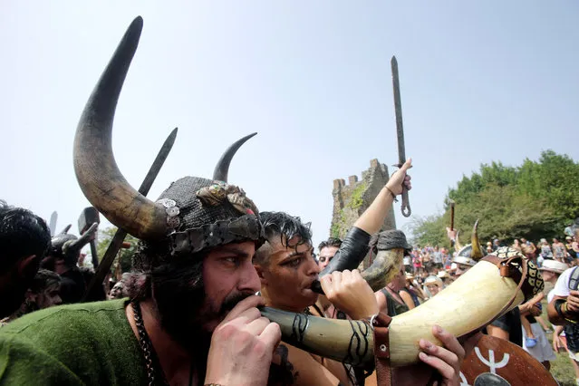 A participant dressed as a Viking blows a horn as he takes part in the annual Viking festival of Catoira in north-western Spain on August 5, 2018. (Photo by Miguel Vidal/Reuters)