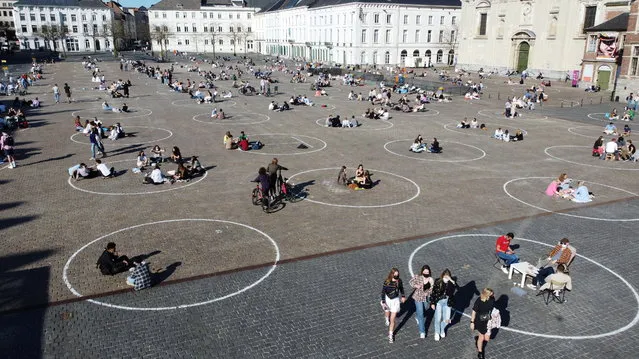 People relax inside circles painted by local authorities at Saint Peter's Square (Sint-Pietersplein) to encourage respect in social distancing amid the coronavirus (COVID-19) outbreak, in Ghent, Belgium on March 29, 2021. (Photo by Bart Biesemans/Reuters)