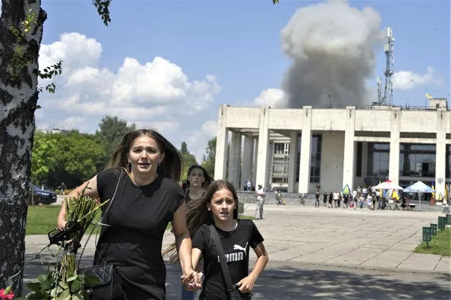 A family runs from an explosion after a Russian rocket attack on residential neighborhood in Pervomaiskyi, Kharkiv region, Ukraine, Tuesday, July 4, 2023. (Photo by Oleksandr Magula/AP Photo)