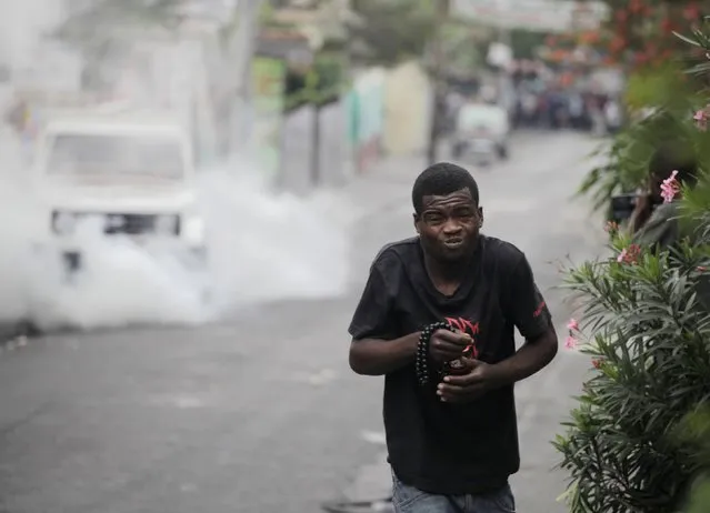 A man grimaces while walking away from tear gas during clashes between demonstrators and police near Champs de Mars in Port-au-Prince February 13, 2015. (Photo by Andres Martinez Casares/Reuters)