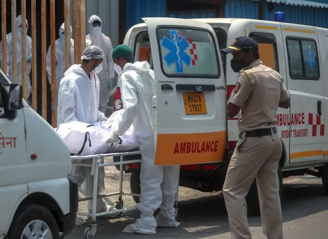 Health workers carry the body of a person who died of COVID-19 outside a field hospital in Mumbai, India, Tuesday, May 4, 2021. COVID-19 infections and deaths are mounting with alarming speed in India with no end in sight to the crisis. (Photo by Rafiq Maqbool/AP Photo)