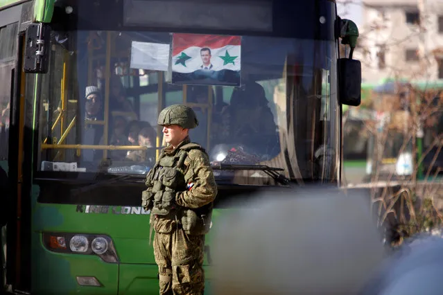 A Russian soldier stands near a bus carrying people who came back to inspect their homes in government controlled Hanono housing district in Aleppo, Syria December 4, 2016. (Photo by Omar Sanadiki/Reuters)