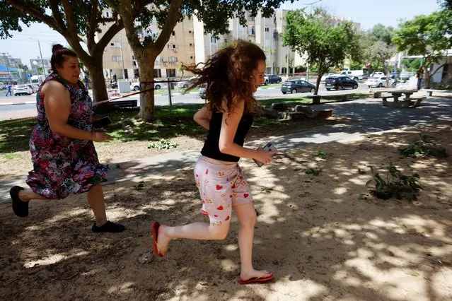 A woman and teen run as a siren sounds warning of an incoming rocket launched from the Gaza Strip, in Ashkelon, southern Israel on May 11, 2021. (Photo by Amir Cohen/Reuters)