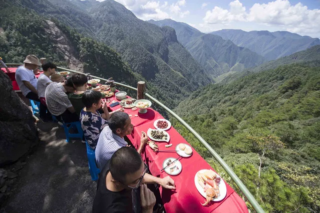 Tourists enjoy food at a restaurant built on the cliff of Longquan Mountain on September 19, 2018 in Lishui, Zhejiang Province of China. Over 100 tourists experienced the newly opened restaurant on suspended plank road of Longquan Mountain on Wednesday. (Photo by VCG/VCG via Getty Images)