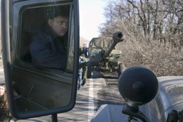 A driver is reflected in the side mirror of a separatist self-proclaimed Donetsk People's Republic army truck towing a mobile artillery cannon, as they pull back from Donetsk, February 24, 2015.
 REUTERS/Baz Ratner (UKRAINE - Tags: POLITICS CIVIL UNREST CONFLICT MILITARY)