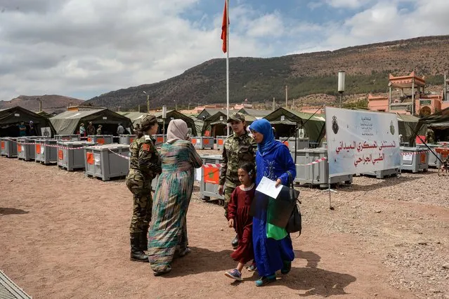 A woman walks with x-rays and a child at the military field hospital for earthquake survivors in the village of Asni in al-Haouz province in the High Atlas mountains of central Morocco on September 12, 2023. Hopes dimmed on September 12 in Morocco's search for survivors, four days after a powerful earthquake killed more than 2,900 people, most of them in remote villages of the High Atlas Mountains. (Photo by AFP Photo/Stringer)