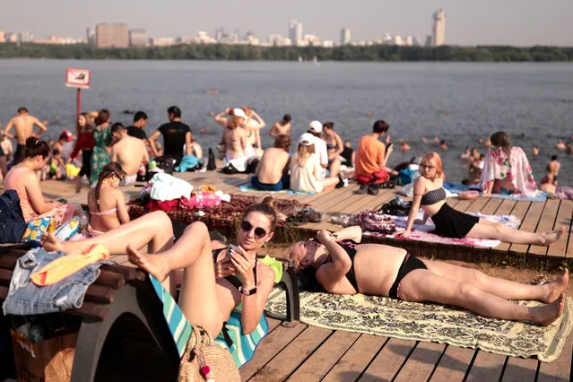 People sunbathe on a beach in Strogino District in northwestern Moscow, Russia on June 23, 2021. (Photo by Sergei Bobylev/TASS)