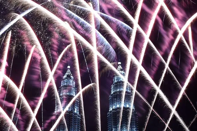 Fireworks illuminate the sky near Malaysia's Petronas Twin Towers during New Year celebrations in Kuala Lumpur on January 1, 2017. (Photo by Mohd Rasfan/AFP Photo)