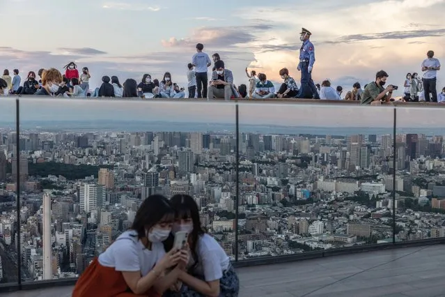 Women take a selfie in front of a mirror reflecting the Tokyo skyline on Shibuya Sky Deck on July 22, 2021 in Tokyo, Japan. Olympics opening ceremony director, Kentaro Kobayashi, has been sacked on the eve of the event after footage emerged in which he appeared to make jokes about the Holocaust. Mr Kobayashi follows a number of other figures involved in the Tokyo Olympic Games who have had to step down for inappropriate remarks. (Photo by Carl Court/Getty Images)