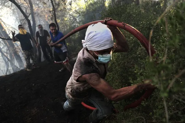 Civil defense workers extinguish a forest fire, at Qobayat village, in the northern Akkar province, Lebanon, Thursday, July 29, 2021. Lebanese firefighters struggled for the second day on Thursday to contain wildfires in the country's north that have spread across the border into Syria, civil defense officials in both countries said. (Photo by Hussein Malla/AP Photo)