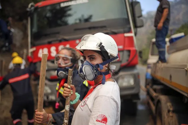 Turkish volunteers stand as they fight wildfires in Turgut village, near tourist resort of Marmaris, Mugla, Turkey, Wednesday, August 4, 2021. (Photo by Emre Tazegul/AP Photo)