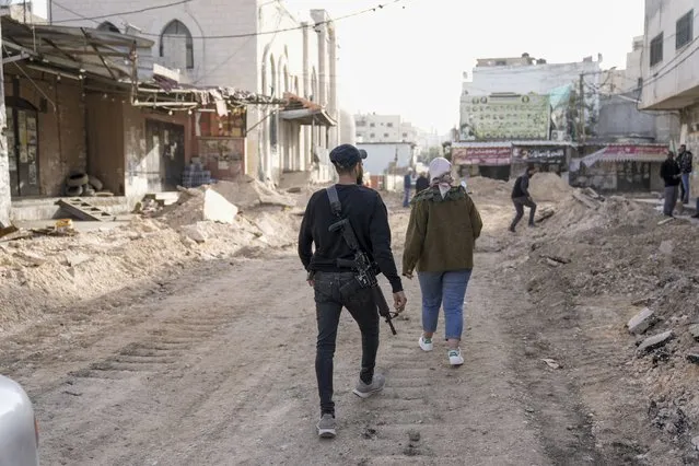 A Palestinians gunman walks on a damaged road following an Israeli army operation in Jenin refugee camp, West Bank, Sunday, November 26, 2023. Israeli forces operating in the occupied West Bank killed at least eight Palestinians in a 24-hour period, Palestinian health officials said Sunday. (Photo by Majdi Mohammed/AP Photo)