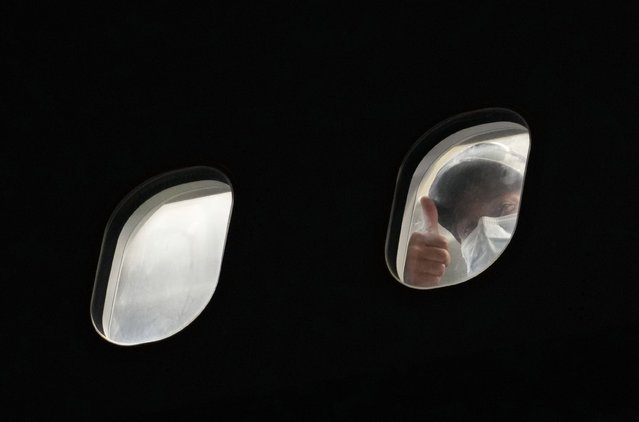 A passenger repatriated from Afghanistan gives a “thumbs up” sign after landing on an RAF Airbus KC2 Voyager aircraft, at RAF Brize Norton, southern England, on August 17, 2021. Britain is sending 900 soldiers back to Afghanistan over the coming days to help with repatriations and evacuations following the rapid Taliban takeover of the country. Officials are aiming to take 1,200 to 1,500 people from Afghanistan a day, with the first flight having landed at a British air force base on Sunday night. (Photo by Christopher Furlong/Pool via AFP Photo)