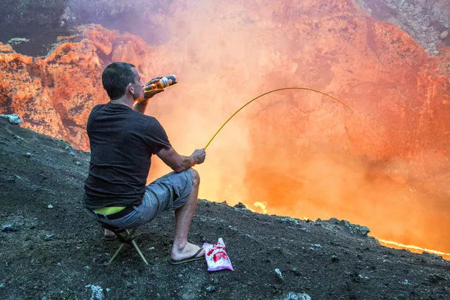 A daredevil has taken roasting on an open fire to a whole new level – heating up his marshmallows over a volcano. Brave Bradley Ambrose filmed colleague Simon Turner as the two descended towards a lava lake inside Marcum Crater in Ambrym, Vanuatu. Simon, from Christchurch, New Zealand, wanted to make the trip more memorable so brought a bottle of beer and some marshmallows to roast. He used a spare tent peg which he took with him on the 400m deep descent towards the lava lake and temperatures of more than 2000F. A seasoned volcano expert, Bradley has made the descent towards the lava lake 12 times in the past – almost three miles of rappelling. (Photo by Bradley Ambrose/Caters News Agency)