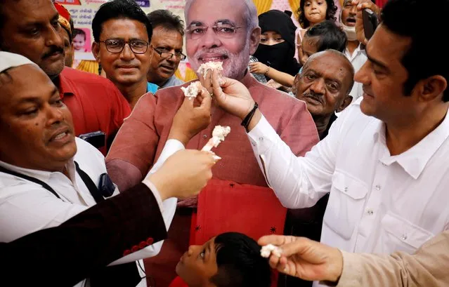 People offer pieces of a cake to a cut-out of India's Prime Minister Narendra Modi as they celebrate his 71st birthday at an event in Ahmedabad, India, September 17, 2021. (Photo by Amit Dave/Reuters)