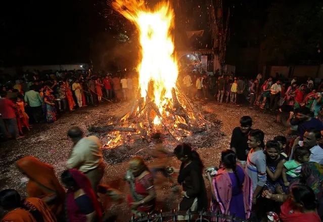 Hindu devotees walk around a bonfire during a ritual known as “Holika Dahan” which is part of Holi festival celebrations, in Ahmedabad, India March 20, 2019. (Photo by Amit Dave/Reuters)