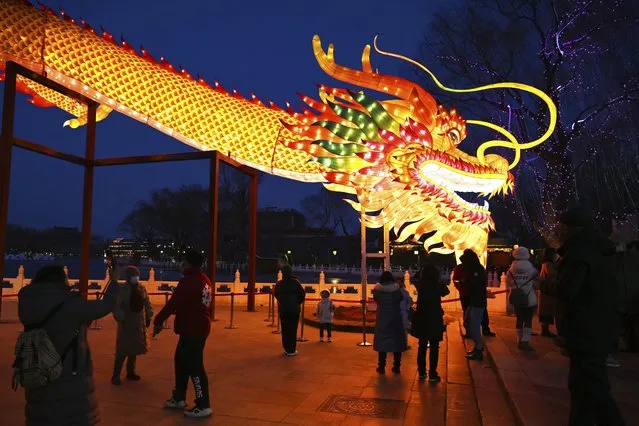 People gather to look at a giant dragon figure at a park in Beijing on February 9, 2024, which marks the eve of the Lunar New Year of the Dragon. (Photo by Greg Baker/AFP Photo)