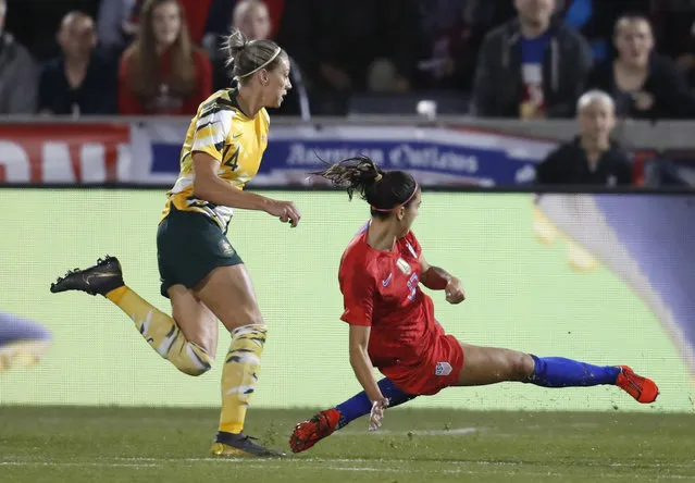 United States forward Alex Morgan, right, falls while scoring a goal as Australia defender Alanna Kennedy looks on during the first half of a friendly soccer match Thursday, April 4, 2019, in Commerce City, Colo. (Photo by David Zalubowski/AP Photo)