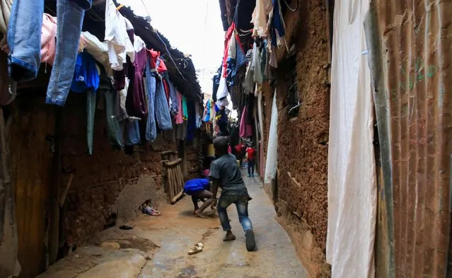 Children play in a courtyard under a hung out laundry amid the coronavirus disease (COVID-19) outbreak, within Kibera slums in Nairobi, Kenya on October 6, 2021. (Photo by Thomas Mukoya/Reuters)