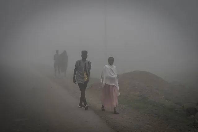 People walk in fog in Amba Giorgis, 40 kilometers Northeast of the city of Gondar, Ethiopia, on September 17, 2021. (Photo by Amanuel Sileshi/AFP Photo)