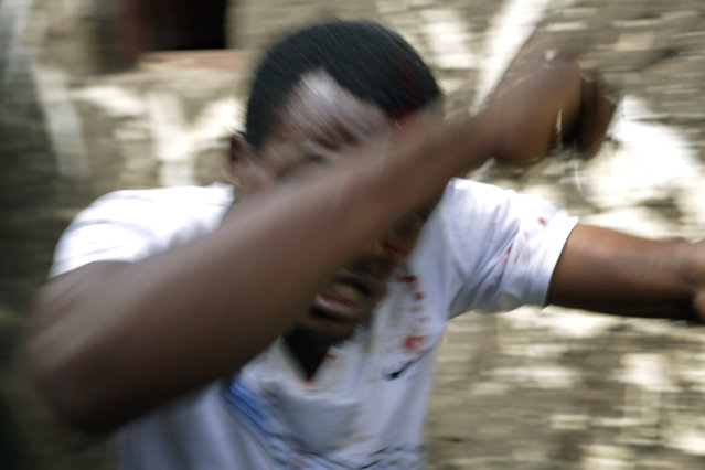 Jean Claude Niyonzima, a suspected member of the ruling party's Imbonerakure youth militia, tries to flee as he pleads for his life at his house, attacked by demonstrators protesting President Pierre Nkurunziza's decision to seek a third term in office in the Cibitoke district of Bujumbura, Burundi, Thursday May 7, 2015. (Photo by Jerome Delay/AP Photo)