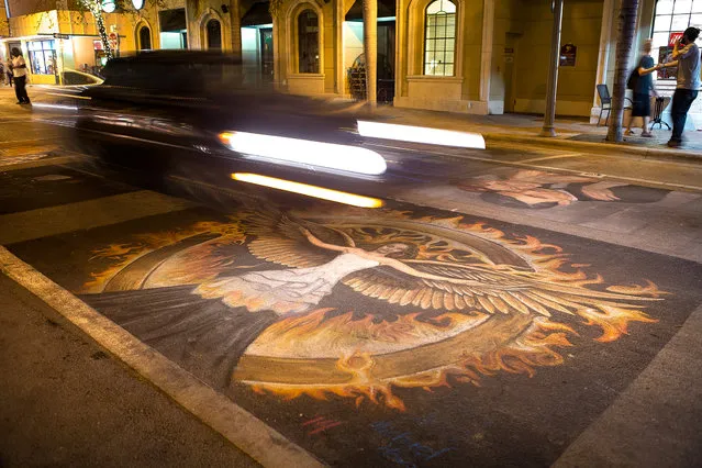 Cars drive over the remnants of artwork from, Sunday night. (Photo by Madeline Gray/The Palm Beach Post)