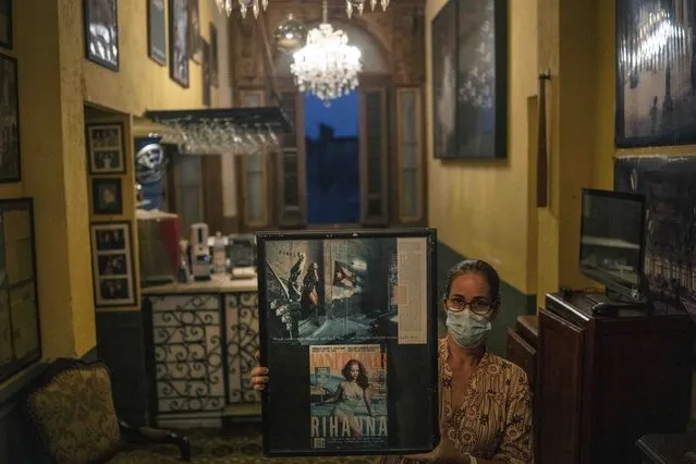 A worker at the restaurant La Guarida, wearing a mask as a precaution amid the spread of COVID-19, poses with photos of singer Rihanna in Havana, Cuba, Wednesday, November 3, 2021. (Photo by Ramon Espinosa/AP Photo)