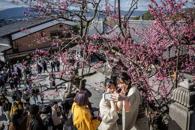 In this picture taken on March 10, 2024, women take selfies in front of a plum tree at Kiyomizu-dera Temple in Kyoto. (Photo by Yuichi Yamazaki/AFP Photo)