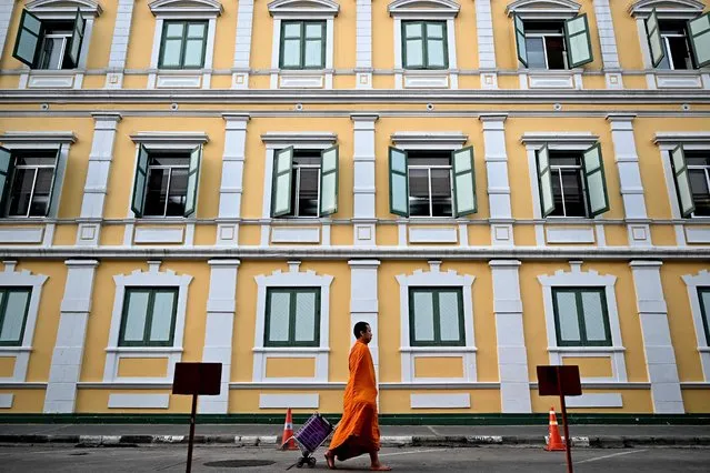 A Buddhist monk walks barefoot past Thailand's Ministry of Defence in Bangkok on March 14, 2024. (Photo by Manan Vatsyayana/AFP Photo)