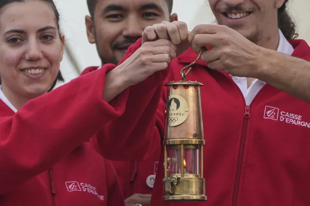 The staff on the Belem hold the Olympic flame with Tony Estanguet, President of Paris 2024 during a ceremony before the departure of the Flame to France at the port of Piraeus, in Greece, for the 2024 Paris Games, on Saturday, April 27, 2024. The flame boarded the Belem, a French three-masted sailing ship, built in 1896, to be transported to the French port of Marseille. (Photo by Petros Giannakouris/AP Photo)