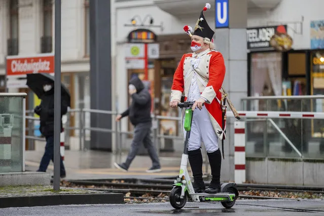 A carnival reveller rides an electric scooter near the Severinstor gate in Cologne, Germany, Monday, February 15, 2021. Because of the coronavirus pandemic the traditional carnival parade in the city are canceled. (Photo by Rolf Vennenbernd/dpa via AP Photo)