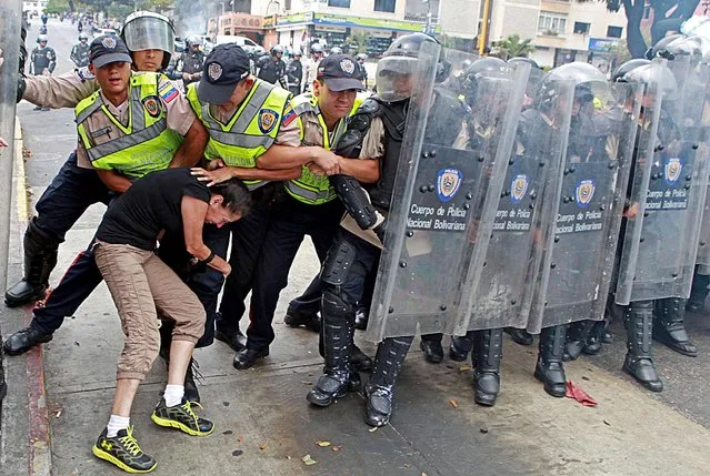 An anti-government activist clashes with riot police during a protest in Caracas on April 1, 2014. In a direct challenge to President Nicolas Maduro, prominent opposition politician Maria Corina Machado vowed to take her seat in the National Assembly despite her ouster by the Supreme Court. (Photo by Federico Parra/AFP Photo)
