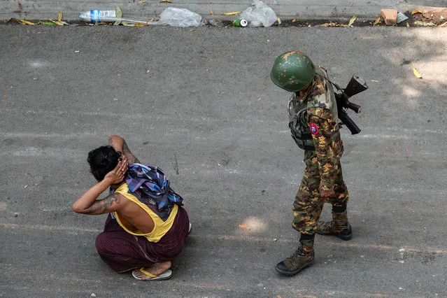 A soldier stands next to a detained man during a demonstration against the military coup in Mandalay on March 3, 2021. (Photo by AFP Photo/Stringer)