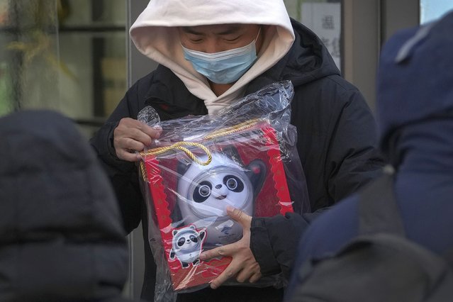 A man holds the Olympic mascot Bing Dwen Dwen doll which he purchased form a store selling 2022 Winter Olympics memorabilia in Beijing, Monday, February 7, 2022. (Photo by Andy Wong/AP Photo)