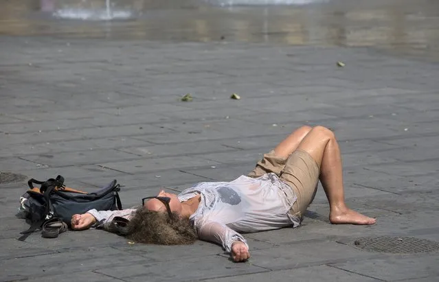 A woman rests next to a fountain on a hot summer day in central Brussels, Belgium, July 2, 2015. The United Nations warned on Wednesday of the dangers posed by hot weather, especially to children and the elderly, as much of Europe sweltered in a heatwave whose intensity it blamed on climate change. (Photo by Yves Herman/Reuters)