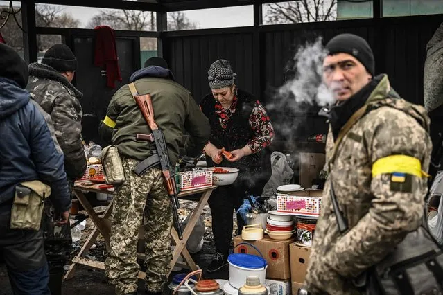 A woman cooks for Ukrainian soldiers at a frontline, northeast of Kyiv on March 3, 2022. (Photo by Aris Messinis/AFP Photo)
