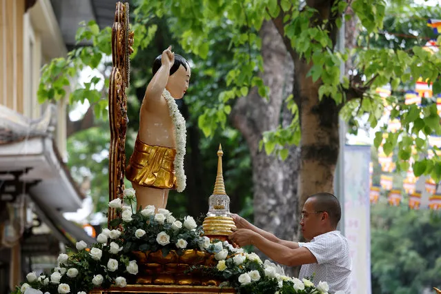 A man places a container holding what is believed to be the relics of Buddha in front of a Child Buddha statue while celebrating the Vesak Day in Quan Su Pagoda, Hanoi, Vietnam May 9, 2017. (Photo by Reuters/Kham)