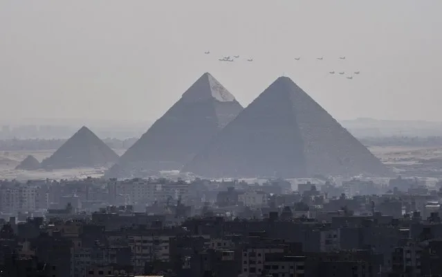 A picture taken from the 24th floor of a building in down town Cairo, shows three French made  Rafale fighter jets (front) flying with other Egyptian air force warplanes above the great pyramids in Giza, on the outskirts of the Egyptian capital, on July 21, 2015. Egypt took delivery of three Rafale fighter jets from France, the first of 24 warplanes sold in a 5.2 billion euro ($5.6 billion) deal earlier this year. (Photo by Khaled Desouki/AFP Photo)