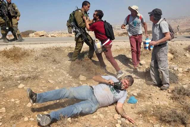 An Israeli activist lies injured on the floor after he was pushed by an Israeli soldier (top) during a demonstration against Israeli land confiscation and the cutting of water supply for Palestinians villages, in the southern area of the West bank town of Hebron, on September 17, 2021. (Photo by Hazem Bader/AFP Photo)