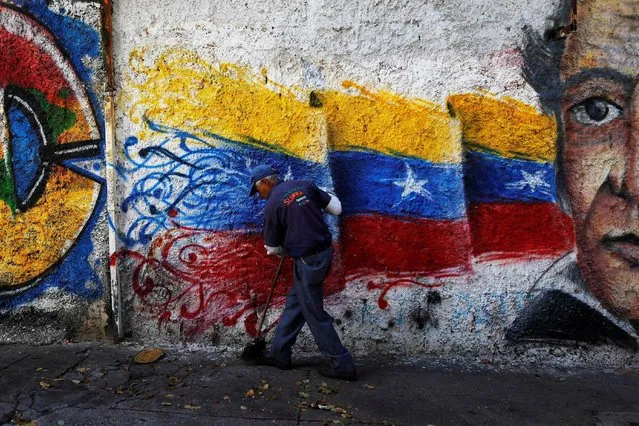 A street cleaner works in front of a graffiti with the colours of the Venezuelan flag, on a street in Caracas, Venezuela, June 8, 2016. (Photo by Ivan Alvarado/Reuters)