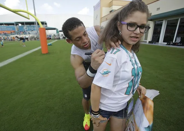 Miami Dolphins cornerback Brent Grimes autographs a shirt for Lexi Cornell, 11, of West Palm Beach, Fla., at NFL football training camp, Tuesday, August 4, 2015, in Davie, Fla. (Photo by Wilfredo Lee/AP Photo)