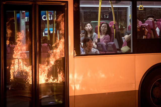 Flames from a burning barricade lit by pro-democracy protesters is reflected in the windows of a passing bus as passengers watch on during a protest gathering in front of Mong Kok police station on September 22, 2019 in Hong Kong, China. Pro-democracy protesters have continued demonstrations across Hong Kong, calling for the city's Chief Executive Carrie Lam to immediately meet the rest of their demands, including an independent inquiry into police brutality, the retraction of the word “riot” to describe the rallies, and genuine universal suffrage, as the territory faces a leadership crisis. (Photo by Chris McGrath/Getty Images)