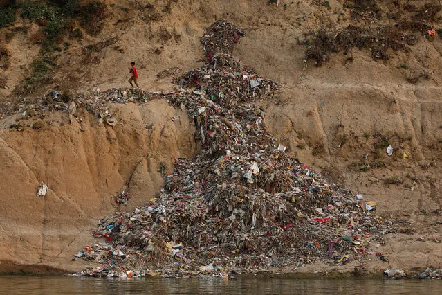 A boy runs past a pile of garbage along the river Ganges in Mirzapur, India, April 19, 2017. India's holy Ganges begins as a crystal clear river high in the icy Himalayas but pollution and excessive usage transforms it into toxic sludge on its journey through burgeoning cities, industrial hubs and past millions of devotees. Worshipped by a billion Hindus and a water source for 400 million, “Mother Ganga” is dying, despite decades of government efforts to save it. (Photo by Danish Siddiqui/Reuters)