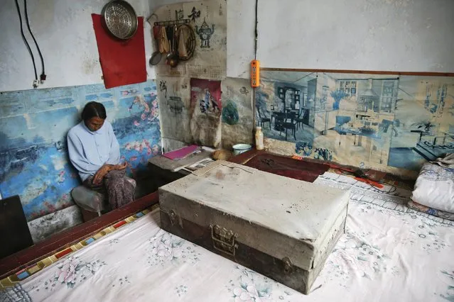 Chinese former “comfort woman” Ren Lane sits behind a suitcase with a shroud, which she prepared for her death, after showing it to reporters at her house in Gucheng Town, Shanxi Province, China, July 17, 2015. (Photo by Kim Kyung-Hoon/Reuters)
