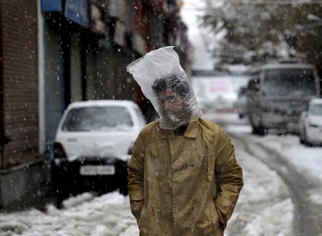 A Kashmiri man cover his head with plastic bag as it snows in Srinagar, Indian controlled Kashmir, Thursday, November 7, 2019. The region received its first snow on Wednesday, bringing temperatures down drastically and affecting air and vehicular traffic. (Photo by Mukhtar Khan/AP Photo)